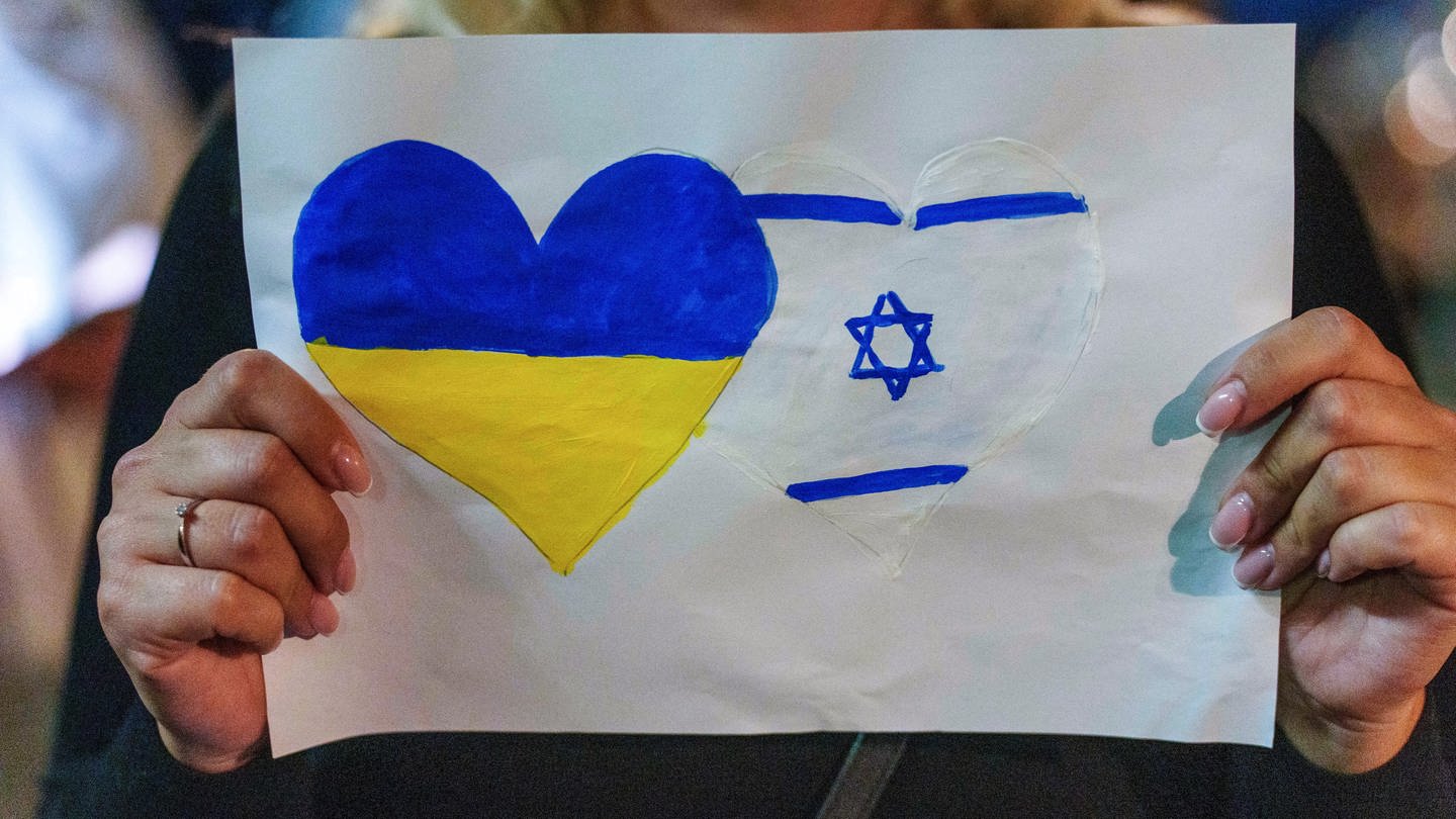 Eine Teilnehmerin drückt ihre Solidarität mit der Ukraine und Israel mit einem Plakat aus. Die jüdische Kultusgemeinde Mainz-Rheinhessen und die deutsch-israelische Gesellschaft Mainz haben unter dem Motto 