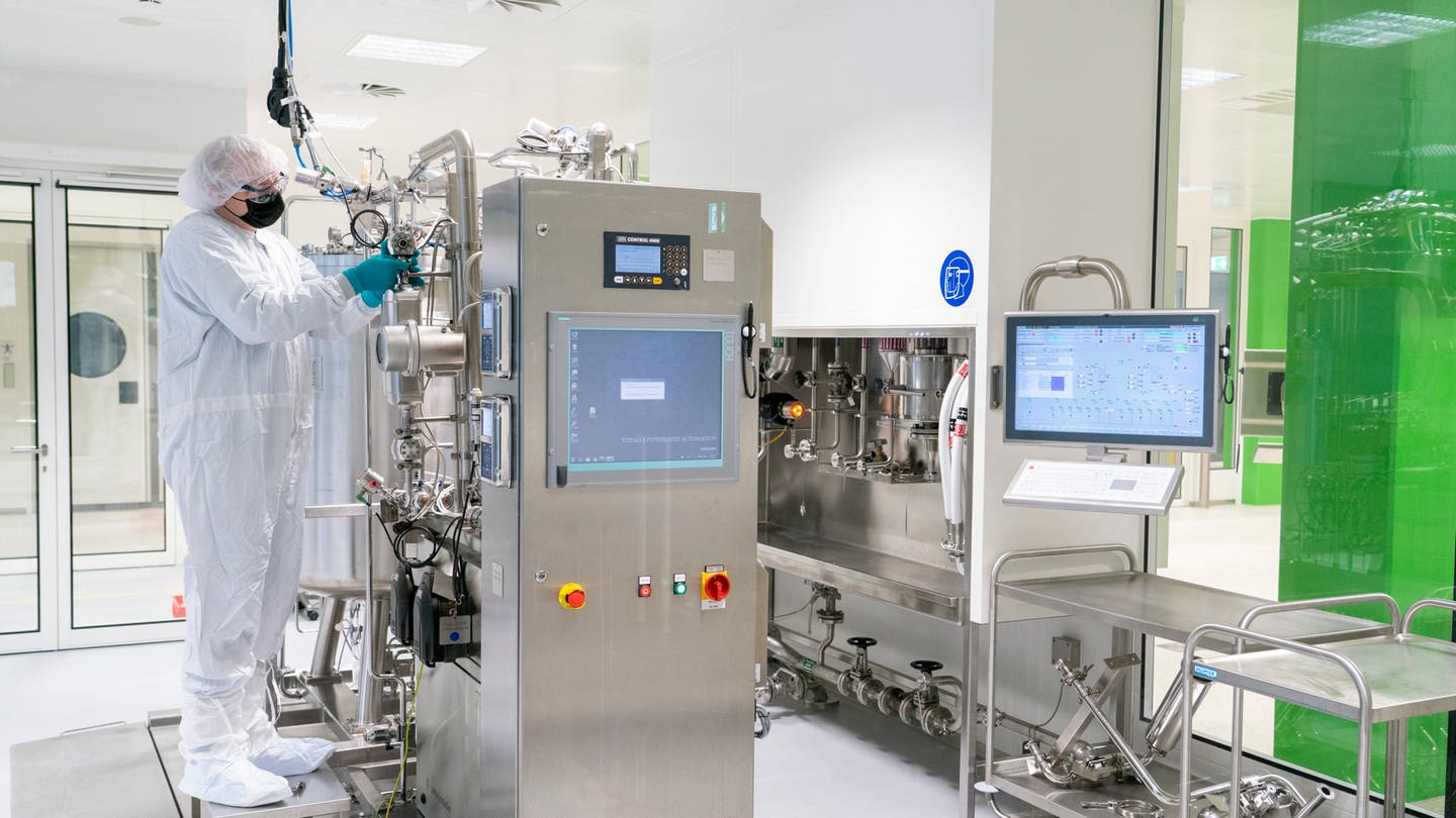 Ein Mitarbeiter arbeitet in der Impstoffproduktion der Bayer AG an einer Maschine (Foto: dpa Bildfunk, picture alliance/dpa/Landesregierung Nordrhein-Westfalen | Michael Rennertz)