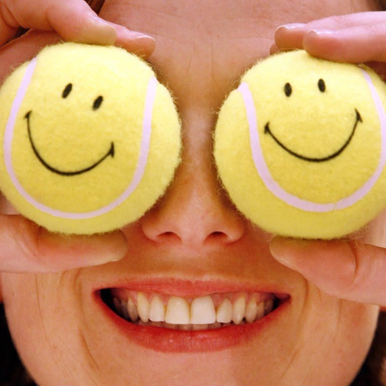 Eine Frau hält sich zwei Tennisbälle mit Smileys vor die Augen  (Foto: dpa Bildfunk, picture alliance / dpa | Frank Rumpenhorst)