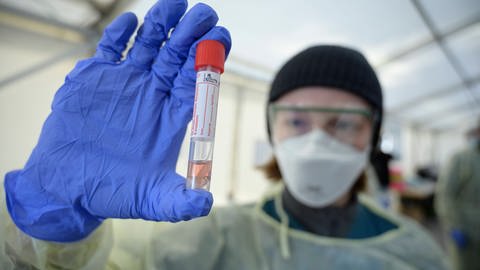 Eine Mitarbeiterin mit der Probe des Nasenabstrichs im Teströhrchen in der Drive-in-Teststation auf das Coronavirus. (Foto: IMAGO, Stefan M Prager)