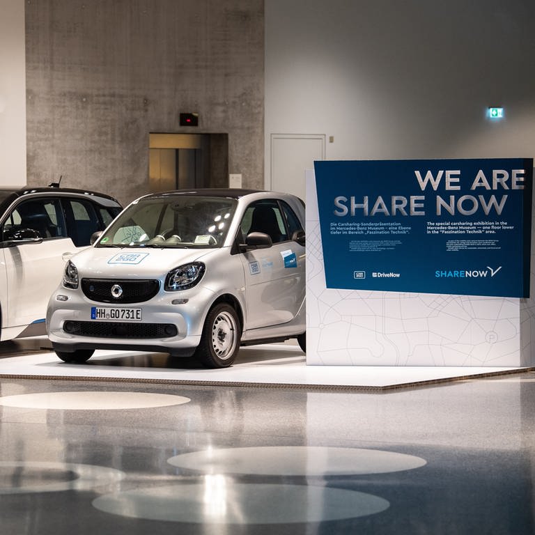 Car-Sharing-Dienst wird an Stellantis verkauft: Ein BMW i3 von DriveNow (l) und ein Smart Fortwo von Car2Go stehen in einer Ausstellung im Mercedes-Benz-Museum neben einem Schild mit der Aufschrift «We are Share Now». (Foto: dpa Bildfunk, picture alliance/dpa | Fabian Sommer)