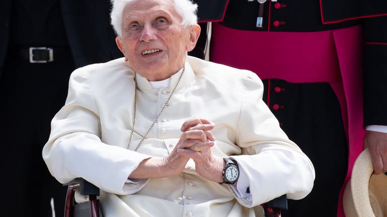 Der emeritierte Papst Benedikt XVI. sitzt mit gefalteten Händen in einem Rollstuhl. (Foto: dpa Bildfunk, picture alliance/dpa/dpa-Pool | Sven Hoppe)