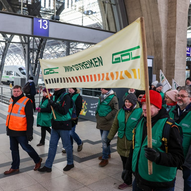 Mitglieder der Lokführergewerkschaft GDL gehen mit einem Banner mit der Aufschrift "Wir streiken" durch ein Bahnhofsgebäude. (Foto: dpa Bildfunk, Picture Alliance)