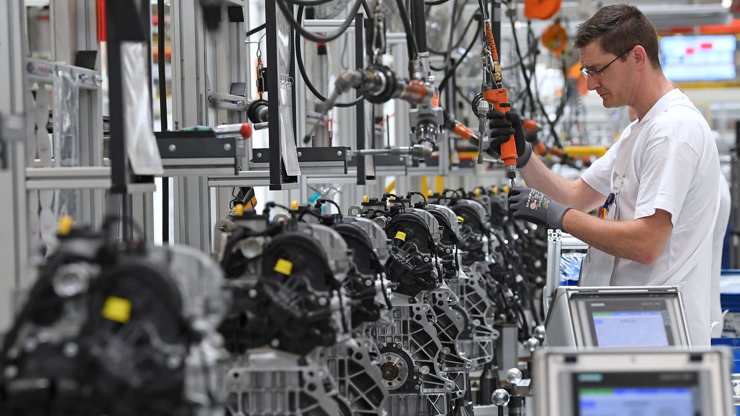 Ein Mann arbeitet in einem Motorenwerk von Volkswagen an der Fertigungslinie an Motoren. (Foto: dpa Bildfunk, picture alliance / Hendrik Schmidt/dpa-Zentralbild/dpa | Hendrik Schmidt)
