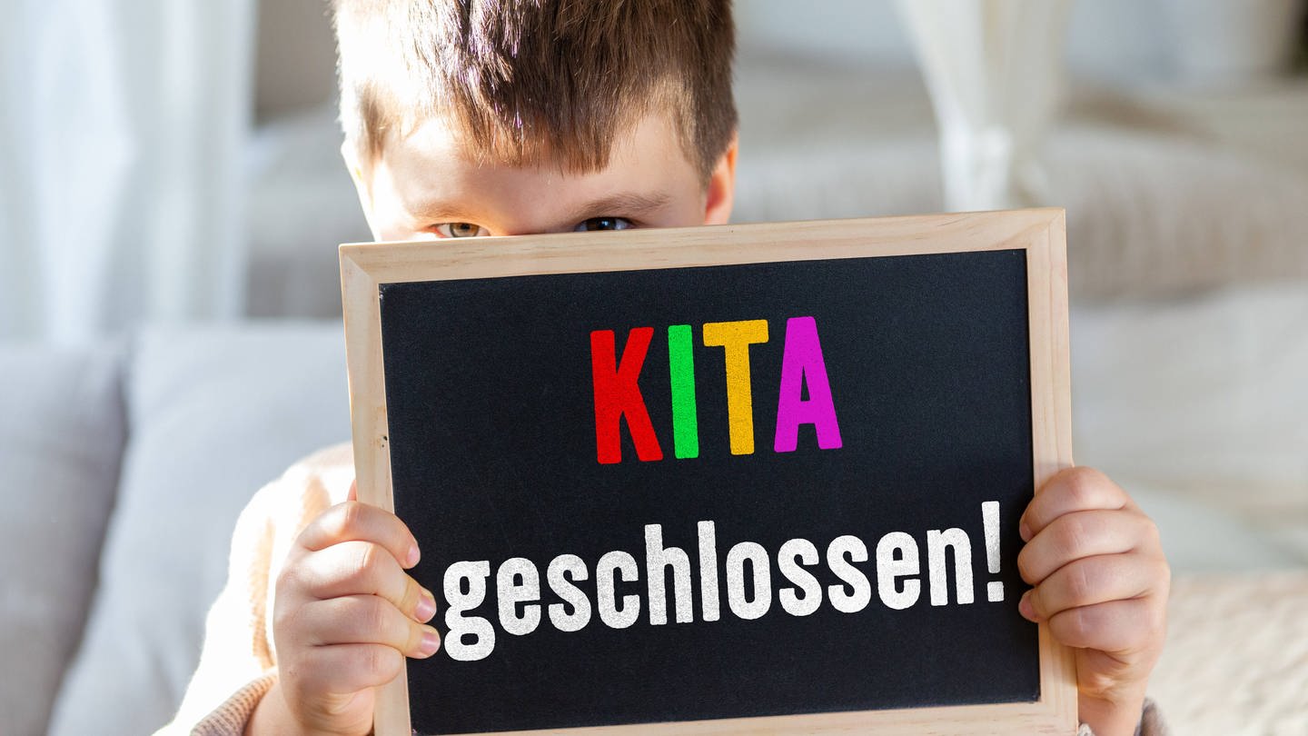 Junge hält Schild: Kita geschlossen (Foto: IMAGO, Bihlmayerfotografie)