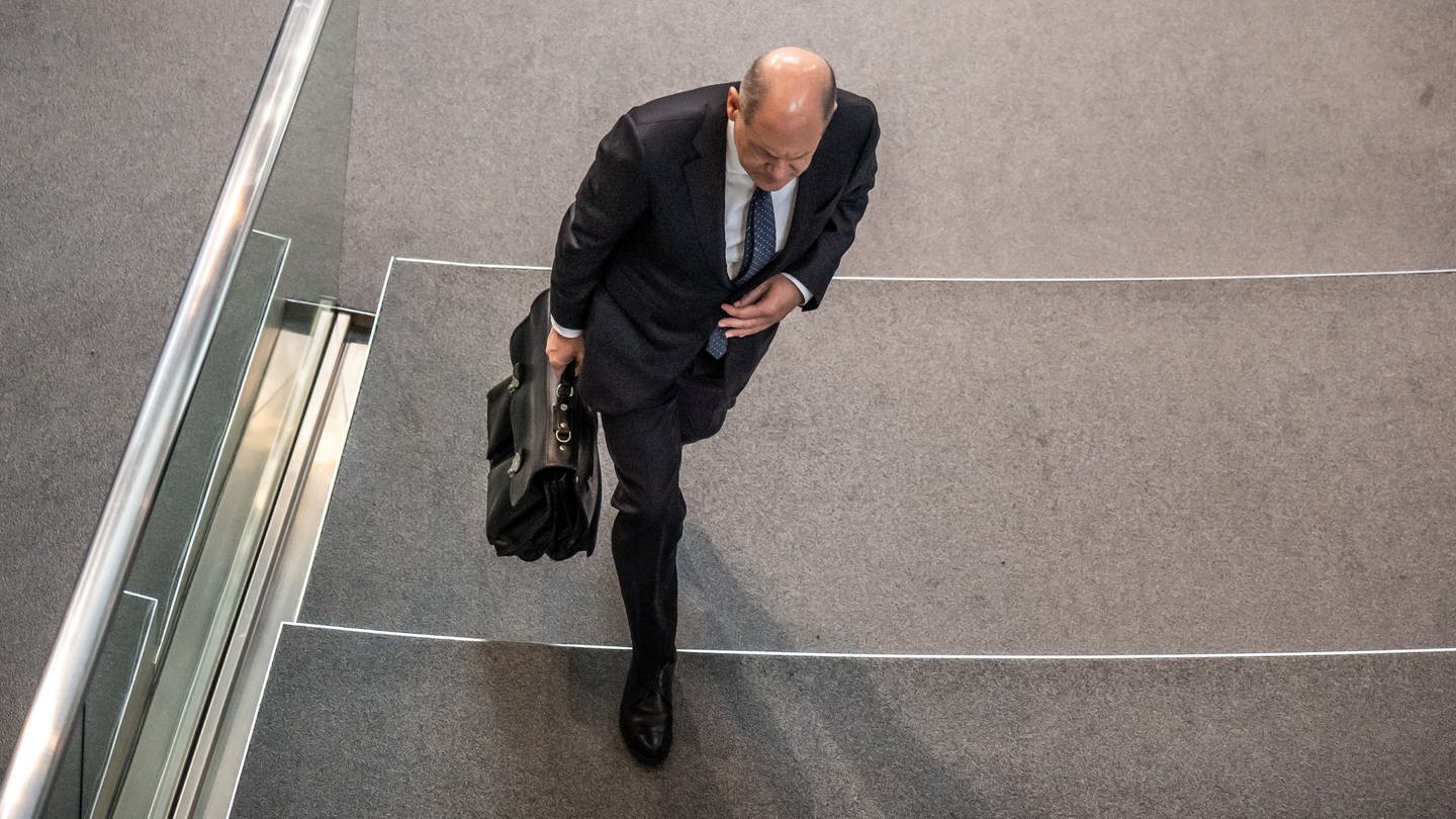 Bundeskanzler Olaf Scholz (SPD) verlässt mit seiner Aktentasche in der Hand im Bundestag den Plenarsaal. (Foto: dpa Bildfunk, picture alliance/dpa | Michael Kappeler)
