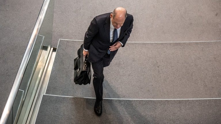 Bundeskanzler Olaf Scholz (SPD) verlässt mit seiner Aktentasche in der Hand im Bundestag den Plenarsaal.