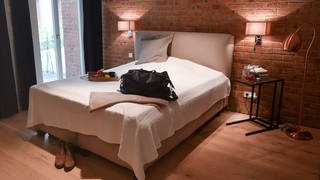 Eine Reisetasche ist in der Wohnung eines Airbnb-Gastgebers auf dem Bett im Schlafzimmer abgestellt. In Baden-Württemberg wird das Zweckentfremdungsverbot von Wohnraum verschärft.  (Foto: dpa Bildfunk, picture alliance/dpa/dpa-Zentralbild | Jens Kalaene)