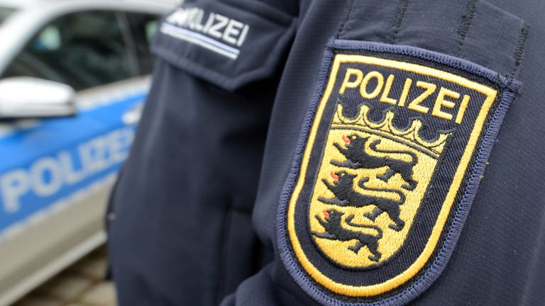 Ein Polizist der baden-württembergischen Polizei ist vor der Polizeidirektion neben einem Polizeifahrzeug zu sehen.  (Foto: dpa Bildfunk, picture alliance/dpa | Patrick Seeger)