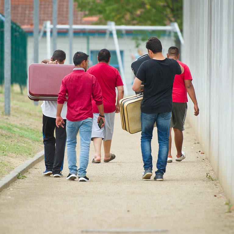 Männer gehen auf einem Weg zu einer Aufnahmeeinrichtung für Flüchtlinge. (Foto: dpa Bildfunk, picture alliance/dpa | Christoph Schmidt)