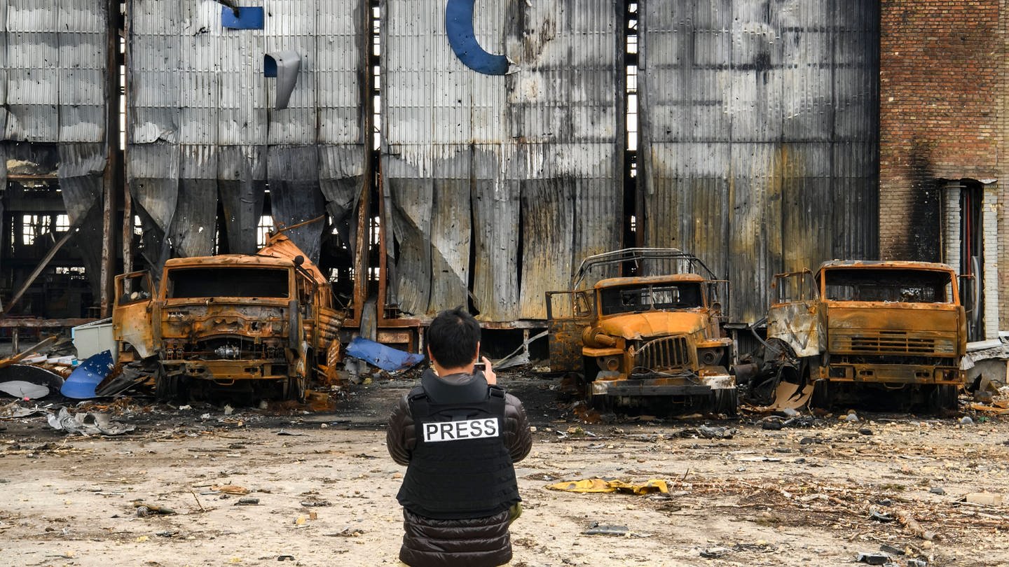 Ein Pressefotograf steht an einem zerstörten Hangar auf dem Gostomel-Flughafen in der Nähe von Kiew.