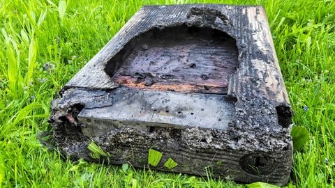 Die verbrannten Überreste des Batteriespeichers einer Photovoltaikanlage liegen auf einer Wiese.  (Foto: © Kreisfeuerwehrverband Calw | Udo Zink)