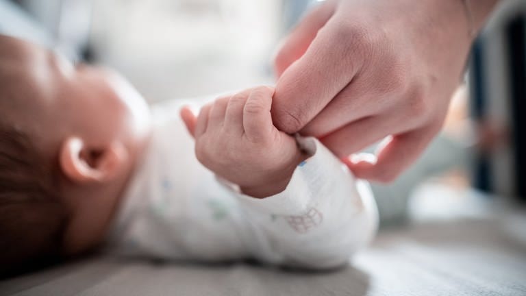 Die Hand eines Babys hält die Hand einer Frau.