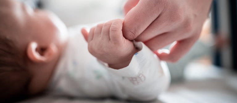 Die Hand eines Babys hält die Hand einer Frau. (Foto: dpa Bildfunk, picture-alliance/dpa, Fabian Strauch)