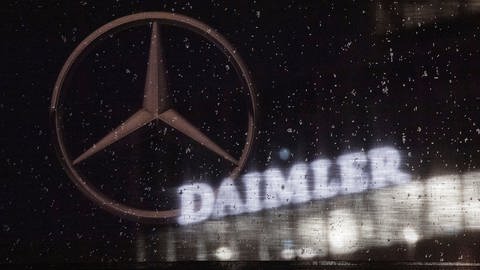 Das Logo der Daimler-AG ist an der Konzernzentrale zu sehen, im Vordergrund ist ein Mercedes-Stern auf einer Flagge abgebildet. (Foto: dpa Bildfunk, picture alliance/dpa | Marijan Murat)