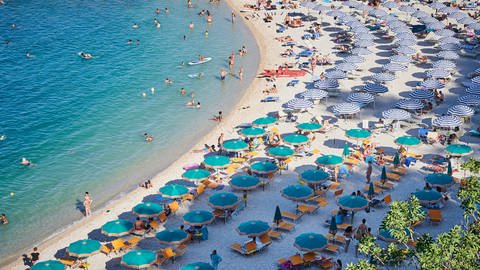 Der Strand an der italienischen Küste bei Sirollo, die zur Provinz Ancona in den Marken gehört, ist voll mit Sonnenschirmen und Badegästen. (Foto: dpa Bildfunk, picture alliance/dpa | Annette Riedl)