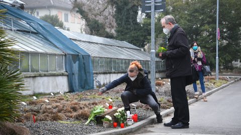 Ein Frau und ein Mann legen auf dem Gelände der Heidelberger Universität Blumen nieder. (Foto: dpa Bildfunk, picture alliance/dpa/Pr-Video | R.Priebe)