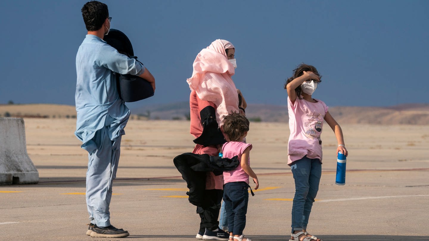 Eine Familie wartet auf der Landebahn des Militärstützpunktes Torrejon nach dem Aussteigen aus einem Flugzeug aus Afghanistan im Rahmen der Evakuierungen. (Foto: dpa Bildfunk, picture alliance/dpa/AP | Andrea Comas)