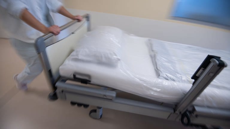 Eine Pflegekarft im Krankenhaus schiebt ein Bett über den Flur. (Foto: dpa Bildfunk, picture alliance/dpa/Marijan Murat)