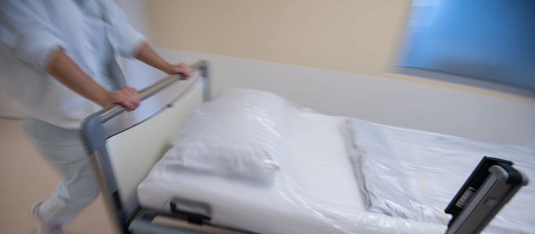 Eine Pflegekarft im Krankenhaus schiebt ein Bett über den Flur. (Foto: dpa Bildfunk, picture alliance/dpa/Marijan Murat)