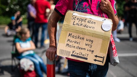 «Stoppt den Lockdown - Masken weg, Merkel weg, Mainstream weg - Freiheit» steht auf dem Schild eines Teilnehmers einer Demonstration der Initiative «Querdenken 711» geschrieben.