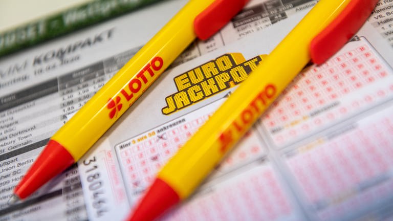 Ein Los für den Eurojackpot und ein Kugelschreiber liegen in einer Lotto-Annahmestelle. (Symbolbild)