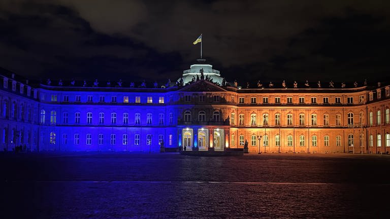 Das Neue Schloss am Schlossplatz in Stuttgart leuchtet in blau-gelben Farben.