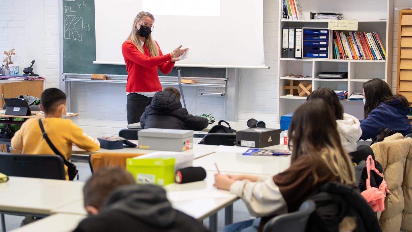 Eine Lehrerin unterrichtet während der Corona-Pandemie mit Maske in einem Klassenraum.