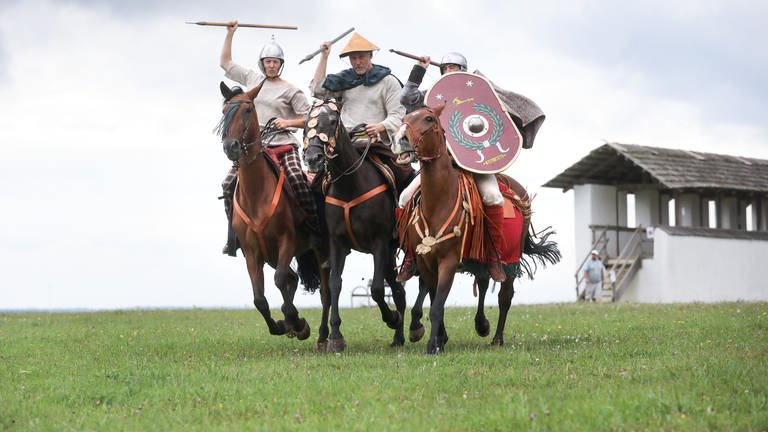 Akteure in Kostümen keltischer Reiterinnen und Reiter führen im Freilichtmuseum Heuneburg während eines Aktionstages antike Reitkunst vor.