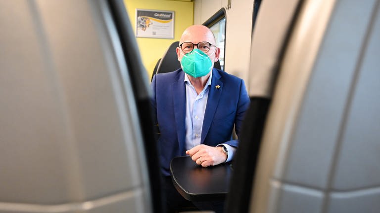 Winfried Hermann (Grünen), der Verkehrsminister von Baden-Württemberg, sitzt in einem Regionalzug und trägt eine FFP2-Maske.  (Foto: dpa Bildfunk, picture alliance/dpa | Bernd Weissbrod)