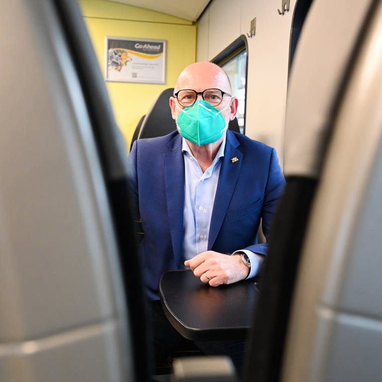 Winfried Hermann (Grünen), der Verkehrsminister von Baden-Württemberg, sitzt in einem Regionalzug und trägt eine FFP2-Maske.  (Foto: dpa Bildfunk, picture alliance/dpa | Bernd Weissbrod)
