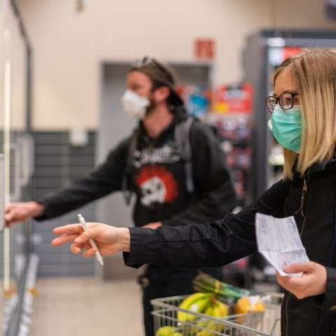 Kunden gehen in einem Supermarkt einkaufen und tragen dabei Mund-und-Nasen-Schutz. (Foto: dpa Bildfunk, Robert Michael/dpa-Zentralbild/dpa)