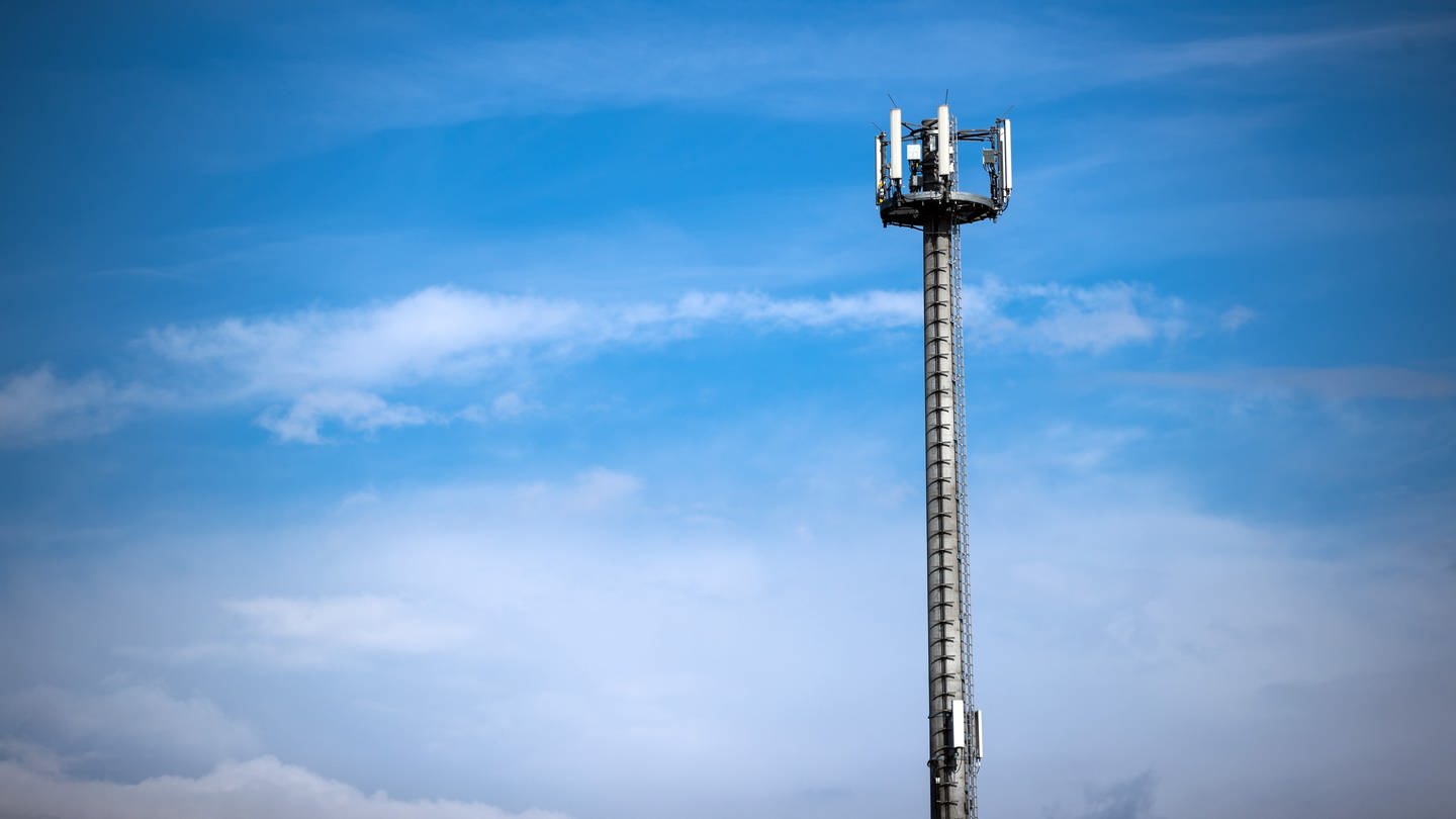 Ein Mast mit verschiedenen Antennen von Mobilfunkanbietern vor blauem Himmel