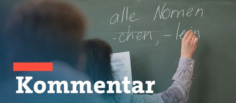 Ein Schüler sitzt in einem Klassenzimmer und schaut nach vorne zu einer Lehrerin, die mit Kreide etwas an die Tafel schreibt.  (Foto: dpa Bildfunk, picture alliance/dpa | Marijan Murat)