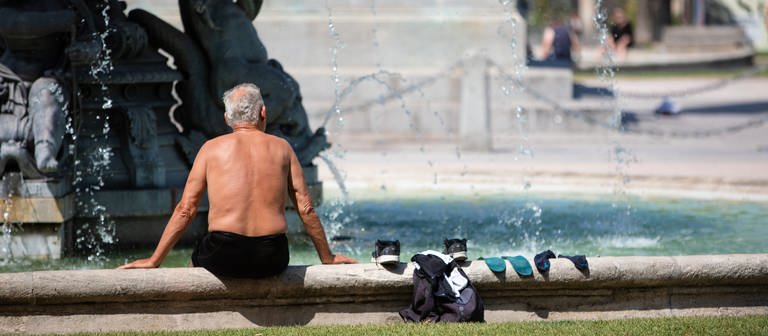Ein Mann kühlt sich bei heißen Temperaturen an einem Brunnen in der Stuttgarter Innenstadt ab. (Foto: dpa Bildfunk, picture alliance/dpa | Christoph Schmidt)
