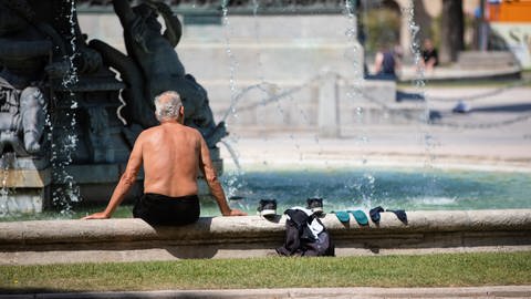Ein Mann kühlt sich bei heißen Temperaturen an einem Brunnen in der Stuttgarter Innenstadt ab. (Foto: dpa Bildfunk, picture alliance/dpa | Christoph Schmidt)