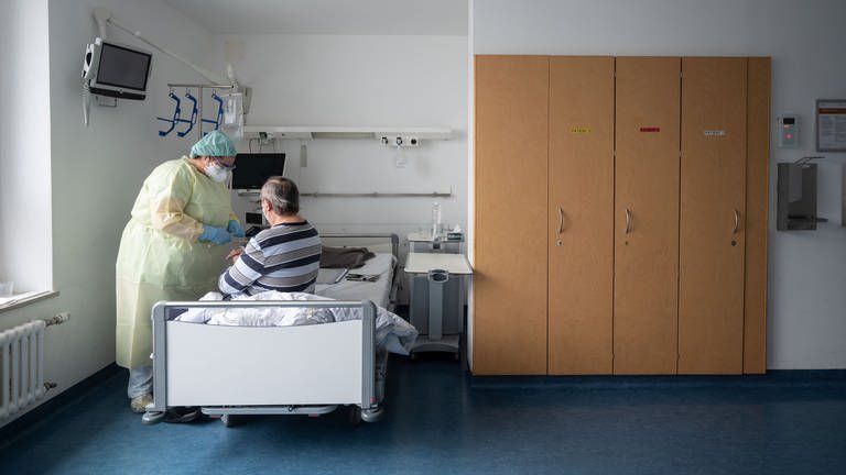 Eine Krankenpflegerin betreut in einem Patientenzimmer einer Covid-19-Station im Klinikum Stuttgart einen Patienten. (Foto: dpa Bildfunk, picture alliance/dpa | Marijan Murat)