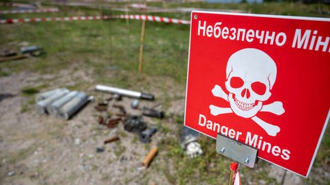 Auf dem Gelände des Antonov Flughafens ist ein Übungsgelände für die Beseitigung von Minen und Kampfmitteln. Am Rand steht ein Warnschild mit der Aufschrift „Danger Mines“. (Foto: dpa Bildfunk, picture alliance/dpa | Christophe Gateau)