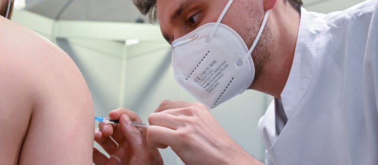 Ein Arzt impft am Klinikum Stuttgart einen Mann in einer Impftstaion in Stuttgart gegen das Coronavirus. (Foto: dpa Bildfunk, picture alliance/dpa | Bernd Weißbrod)