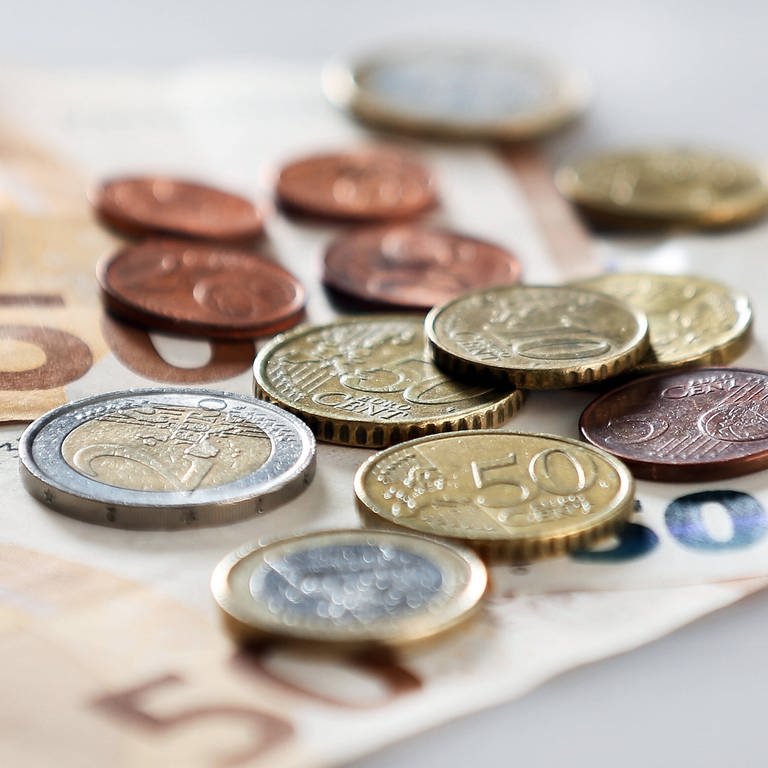 Geldmünzen und Geldscheine liegen verteilt auf einem Tisch. (Foto: IMAGO, IMAGO / avanti)