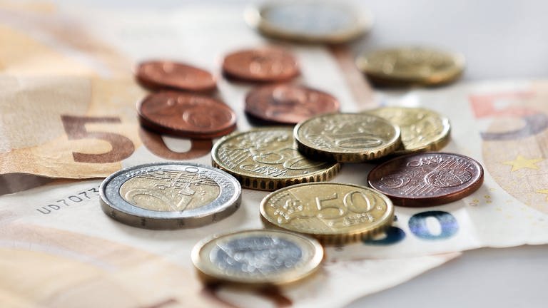 Geldmünzen und Geldscheine liegen verteilt auf einem Tisch. (Foto: IMAGO, IMAGO / avanti)