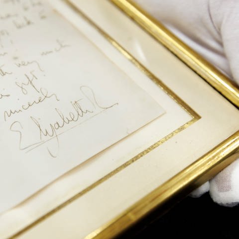 Die Unterschrift von Königin Elisabeth II. auf einer Kopie der Rückseite, welche dem eingerahmten Brief beiliegt. (Foto: dpa Bildfunk, picture alliance/dpa | Julian Rettig)