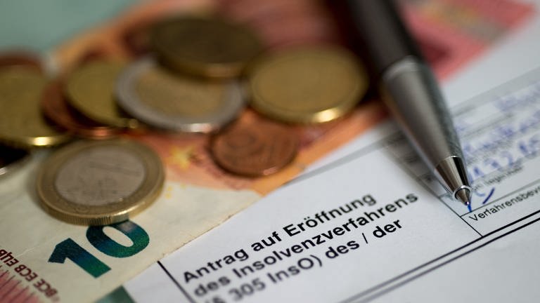 Antrag auf Eröffnung des Insolvenzverfahrens liegt neben Münzen und einem 10-Euro-Schein auf dem Tisch (Symbolbild) (Foto: dpa Bildfunk, picture alliance/dpa | Swen Pförtner)