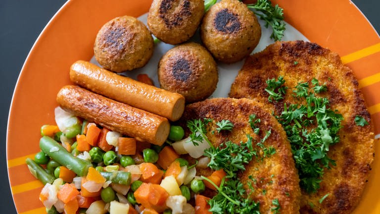 Vegane Falafel, vegane Schnitzel, vegane Würstchen und Gemüse sind auf einem Teller in einer Küche zu sehen. Verbraucherschützer fordern eine verbindliche Kennzeichnung veganer und vegetarischer Lebensmittel. (Foto: picture-alliance / Reportdienste, Picture Alliance)