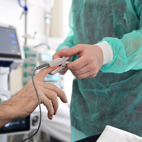 Ein Pfleger legt in einem Krankenzimmer im Klinikum Stuttgart bei einem Patienten ein Messgerät an. (Foto: dpa Bildfunk, picture alliance/dpa | Bernd Weißbrod)