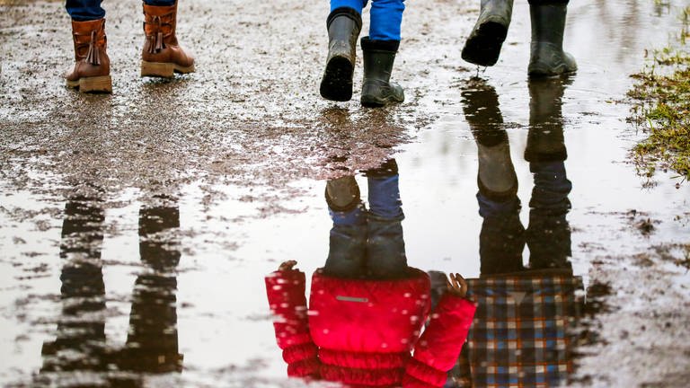 Eine Frau und ihre Kinder gehen auf einem Weg auf dem sich Regenpfützen gebildet haben. (Foto: dpa Bildfunk, picture alliance/dpa | Thomas Warnack (Archiv))