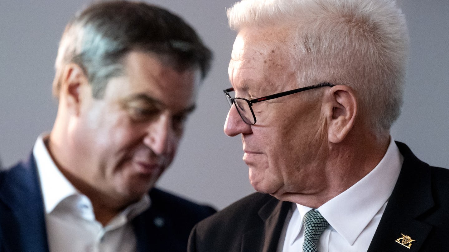 Der Ministerpräsident von Baden-Württemberg, Winfried Kretschmann (Grüne), blickt wirft einen skeptischen Blick über die Schulter zu seinem Amtskollegen Markus Söder (CSU), dem Ministerpräsidenten von Bayern (Archivbild). (Foto: dpa Bildfunk, picture alliance/dpa | Sven Hoppe)