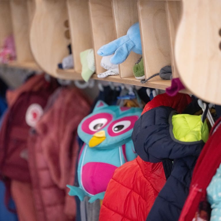 Jacken und Taschen hängen an einer Garderobe einer Kita.  (Foto: dpa Bildfunk, picture alliance/dpa | Marijan Murat)