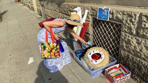 Frau zieht eine Pfanne aus einer "Geschenkekiste" in Stuttgart-West (Foto: SWR)