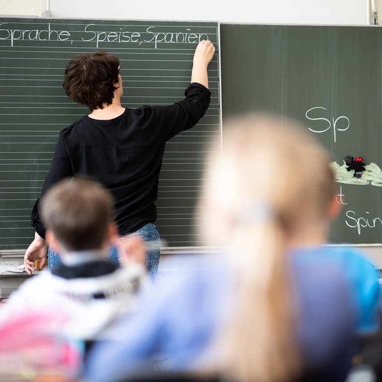 Eine Lehrerin schreibt in einer Grundschule Wörter mit "Sp" am Anfang an eine Tafel.  (Foto: dpa Bildfunk, picture alliance/dpa | Sebastian Gollnow)